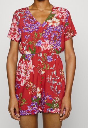 Krótki, czerwony kombinezon w kwiaty, z dekoltem w serek, krótkimi rękawami, elastyczną talią oraz wzorem kwiatowym w odcieniach fioletu, różu i zieleni.