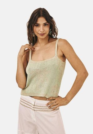 Top corto de punto verde menta con escote cuadrado y tirantes delgados, combinado con pantalones claros que presentan un acolchado decorativo.