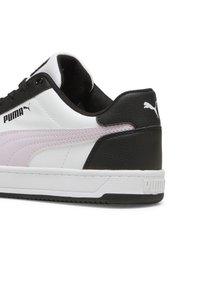 Zapatilla negra, blanca y rosa con parte superior de cuero suave, cuello acolchado en el tobillo y talón texturizado. Presenta el logo de Puma y suela de goma.