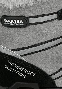 Szare wodoodporne zimowe buty z czarnymi akcentami, z futrzanym kołnierzem, odblaskowymi paskami oraz etykietą z logo "BARTEK WINTER ACTIVITIES."