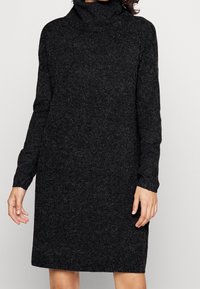 Stickad polotröja klänning i mörkgrått med långa ärmar. Har en avslappnad passform och mjuk textur, når till mitten av låret.