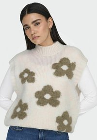 Chunky Strickweste in Pastellrosa mit braunen Blumenmustern. Sie hat einen hohen Kragen, kurze Ärmel und eine weiche, strukturierte Oberfläche.