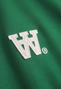 Green fabric with a textured, white embroidered logo featuring "W" and a registered trademark symbol on the right.
