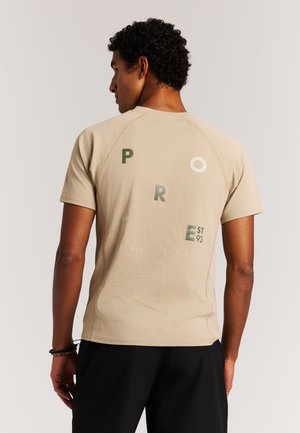 Beige atletisch T-shirt met een gestructureerde stof, korte mouwen en een groot bedrukt ontwerp op de achterkant in groen en wit met de tekst "PRO TE EST 93."