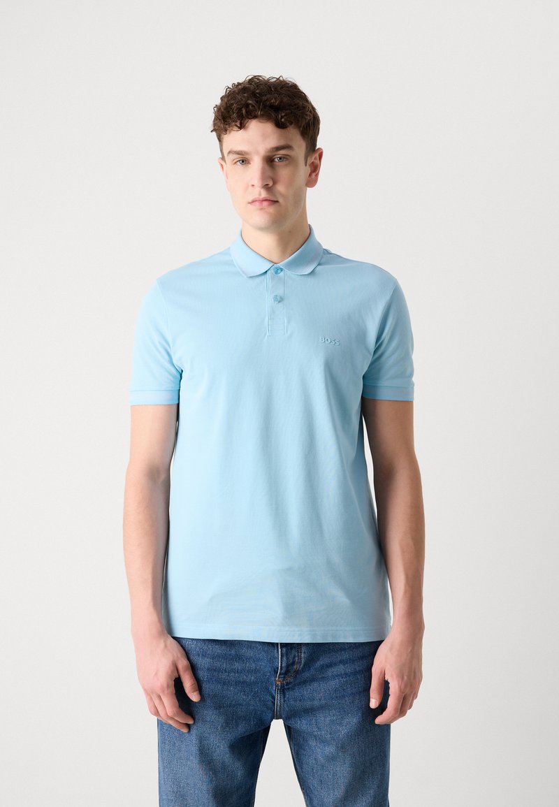 Lichtblauwe polo gemaakt van gladde stof, met een kraag en een knoopsluiting met drie knopen. Geborduurd logo op de linkerkant van de borst. Casual pasvorm.