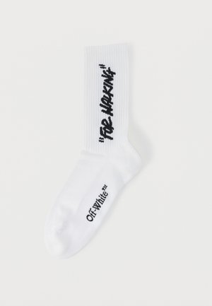 Calcetín blanco acanalado con texto negro "FOR WALKING" en vertical y "Off-White™" en horizontal cerca del pie.