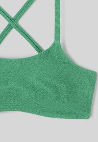 Haut de bikini texturé vert avec des bretelles croisées, une finition lisse et un décolleté arrondi. Le matériau semble doux et extensible.