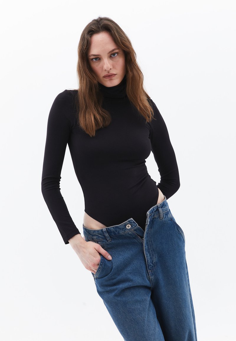 Schwarzer Langarm-Poloshirt-Bodysuit, kombiniert mit blauen Denim-Weitbeinen-Jeans, die über Fronttaschen verfügen und an der Taille locker sitzen.
