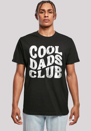 Black cotton t-shirt featuring bold, white distressed text "COOL DADS CLUB." Short sleeves and a round neckline. Casual fit.