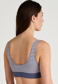 Gestreepte sportbeha in blauw en wit, met een ronde rug en brede banden, gemaakt van zacht, rekbaar materiaal voor comfort en ondersteuning.