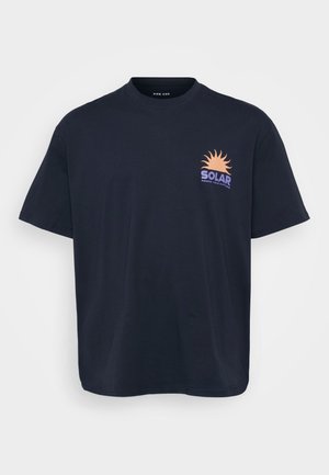 Must must t-särk mustast puuvillast, millel on graafika päikesest ja "SOLAR" tekst oranžis ja lillakas toonis. Lühikesed varrukad, ümmargune kaelus, mugav lõige.