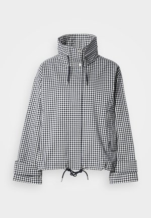 Veste à carreaux noir et blanc avec col montant, boutons-pression à l'avant, ourlet réglable avec cordon de serrage et manches longues avec détails aux poignets.