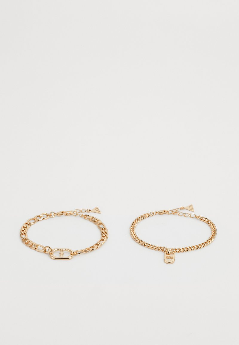 Dos pulseras de cadena en tono dorado, una con un cierre con diseño de corazón y la otra con un pequeño charm rectangular. Ambas tienen un acabado suave.