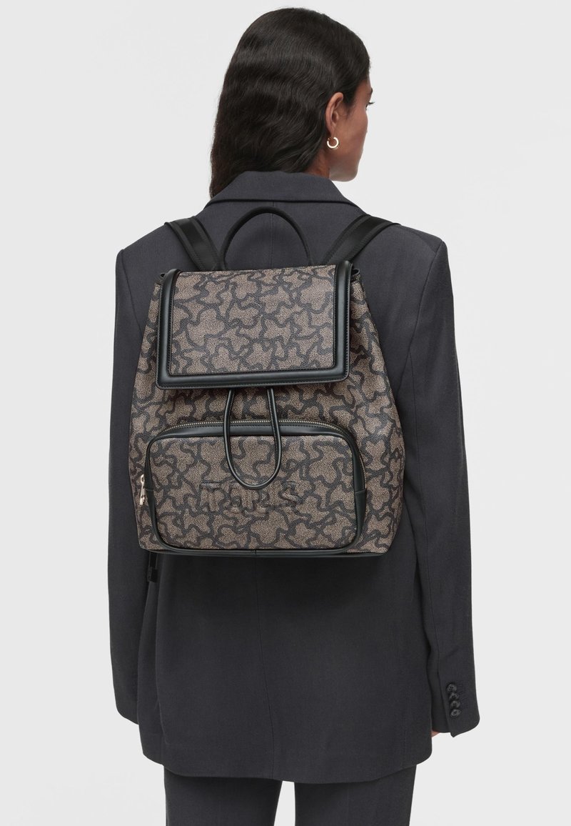 Zaino in tessuto a motivo, grigio e nero, con chiusura a patta e tasca frontale con zip. Spallacci regolabili e dettagli lisci.