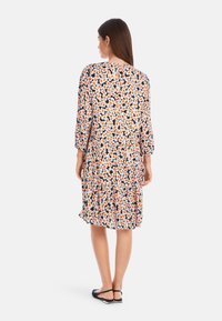 Floral dress with 3/4 sleeves in black, white, orange, and blue colors. Features a tiered bottom hem and relaxed fit. Smooth fabric texture.