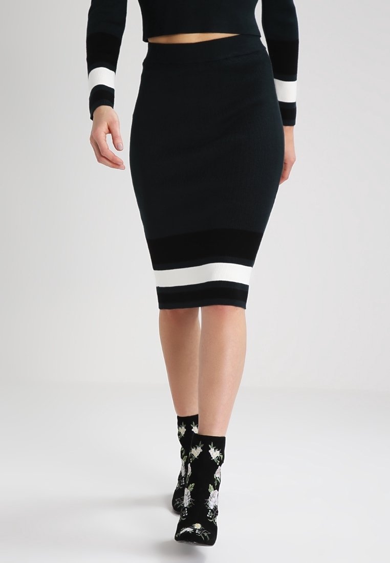 Černá skládaná úzká sukně s bílými horizontálními pruhy na lemu. Doplněna černými kotníkovými botami s květinovou výšivkou.