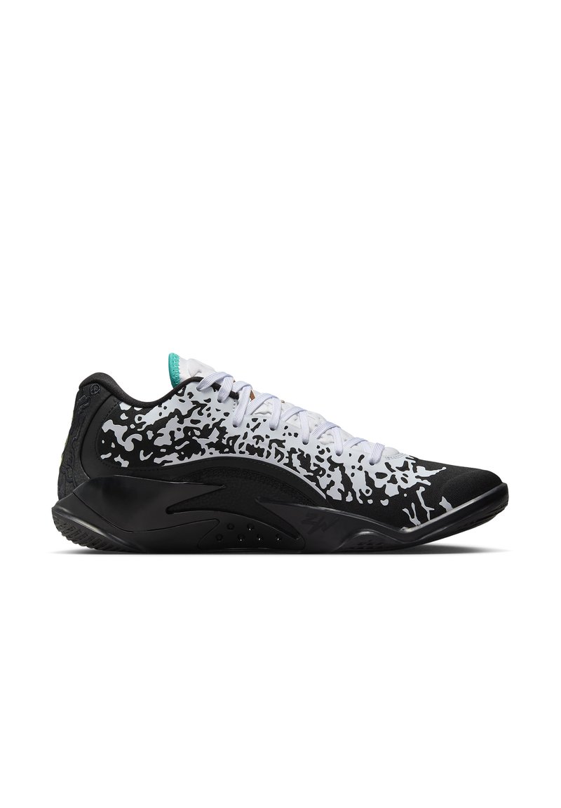 Zapatilla deportiva de perfil bajo con parte superior moteada en negro y blanco, cordones blancos y suela gruesa negra, presentada en vista lateral sobre fondo blanco.