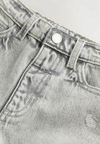 Jean en denim gris avec une texture légèrement déchirée, fermeture à bouton en argent et design classique à cinq poches.