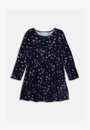 Mornarska obleka z dolgimi rokavi, ki ima cvetlični vzorec v roza in beli barvi. Krilo je razširjeno z naborki in okroglo ovratnikom. Narejena iz mehkega blaga.