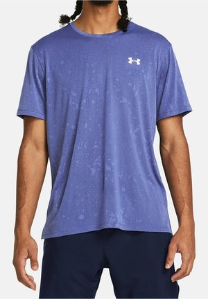 Mand iført en blå Under Armour T-shirt med korte ærmer og diskret mønster samt mørkeblå træningsshorts, stående mod en hvid baggrund.