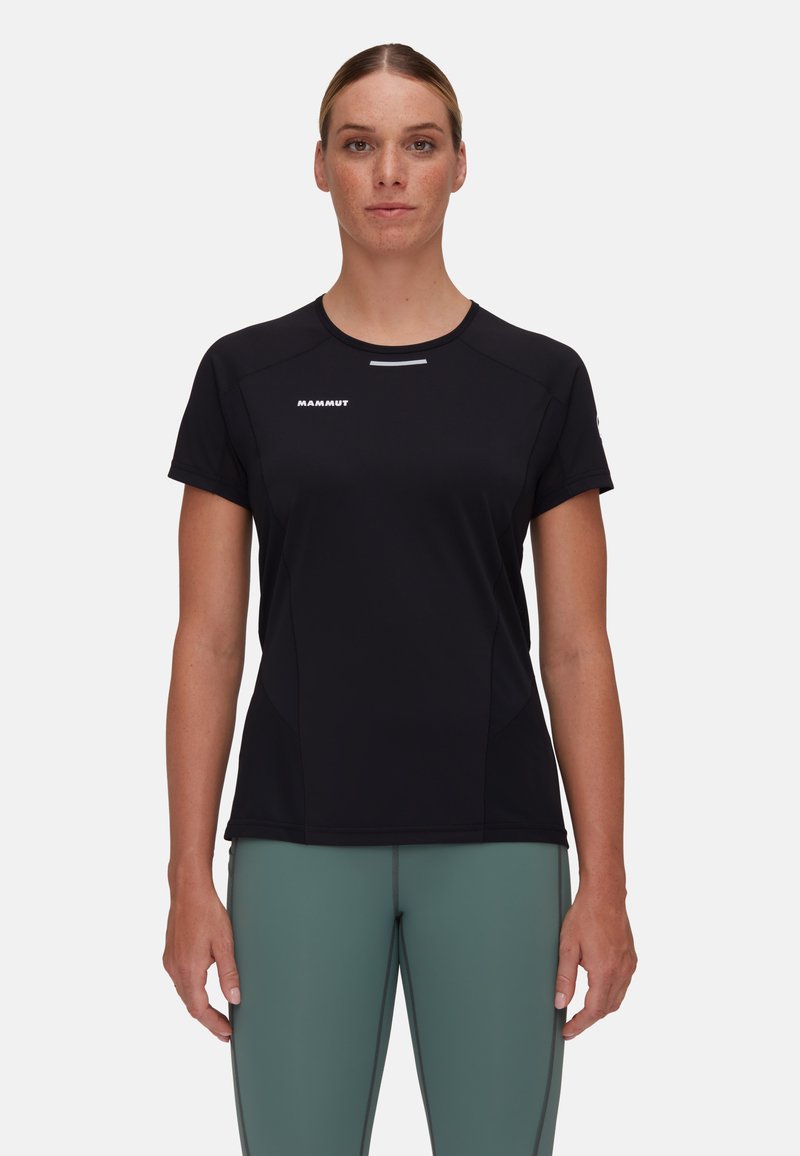 Svart atletisk t-shirt med korta ärmar, fukttransporterande material, diskret logotyp på bröstet och figurnära design, matchad med gröna tights.