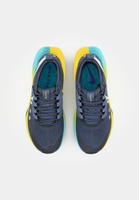Scarpe da ginnastica Nike in blu navy, giallo e turchese. Presentano una tomaia in mesh, un design perforato e una suola in gomma con accenti vivaci.