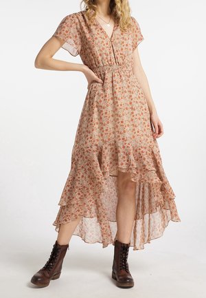 Robe florale dans des tons chauds avec des couches volantées, des manches courtes, un col en V et une taille smockée. Associée à des bottes brunes à lacets.