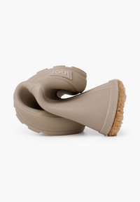 Juguete para perros de ventosa en goma beige con un agarre texturizado, diseño en espiral y una base de fibra natural que imita la forma de un cono.