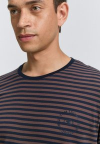 Gestreept T-shirt in bruin en marineblauw, met korte mouwen en een ronde hals. Heeft een logoprint op de borst en een gladde katoenstructuur.