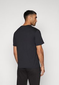 Sort kortærmet t-shirt fremstillet af bomuld, med en klassisk rund hals og en afslappet pasform, samt en glat tekstur. Bageste udsigt vist.