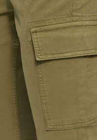 Khaki cargobroek met een grote patchzak aan de zijkant. Gemaakt van duurzaam materiaal met zichtbare stiksels en een gladde textuur.