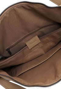 Bruin stoffen interieur van een tas met een ritszak en een glad leren label. De voering is zacht met een subtiele glans.