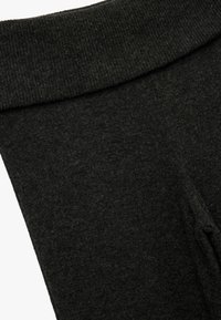 Schwarze, strukturierte Leggings mit einem gerippten Taillenbund, die über eine glatte Stoffoberfläche und eine taillierte Passform für optimale Bewegungsfreiheit verfügen.