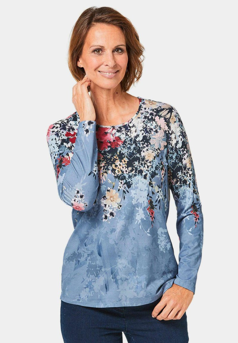 Blumenmuster Langarmhemd in Hellblau, mit lebhaften, bunten Blumen und einem runden Ausschnitt. Weicher, glatter Stoff.