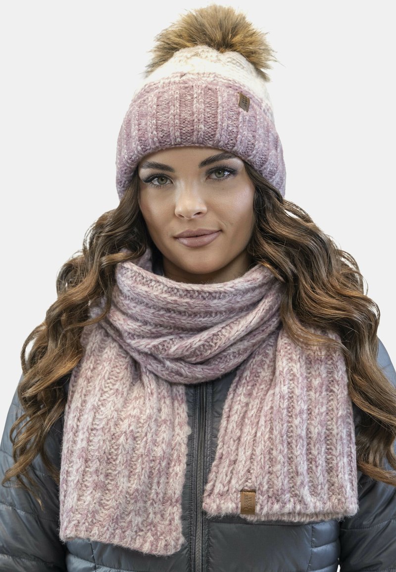 Strikket vinterhat og halstørklæde sæt i lys pink og creme med et struktureret mønster; hatten har en faux fur pompom.