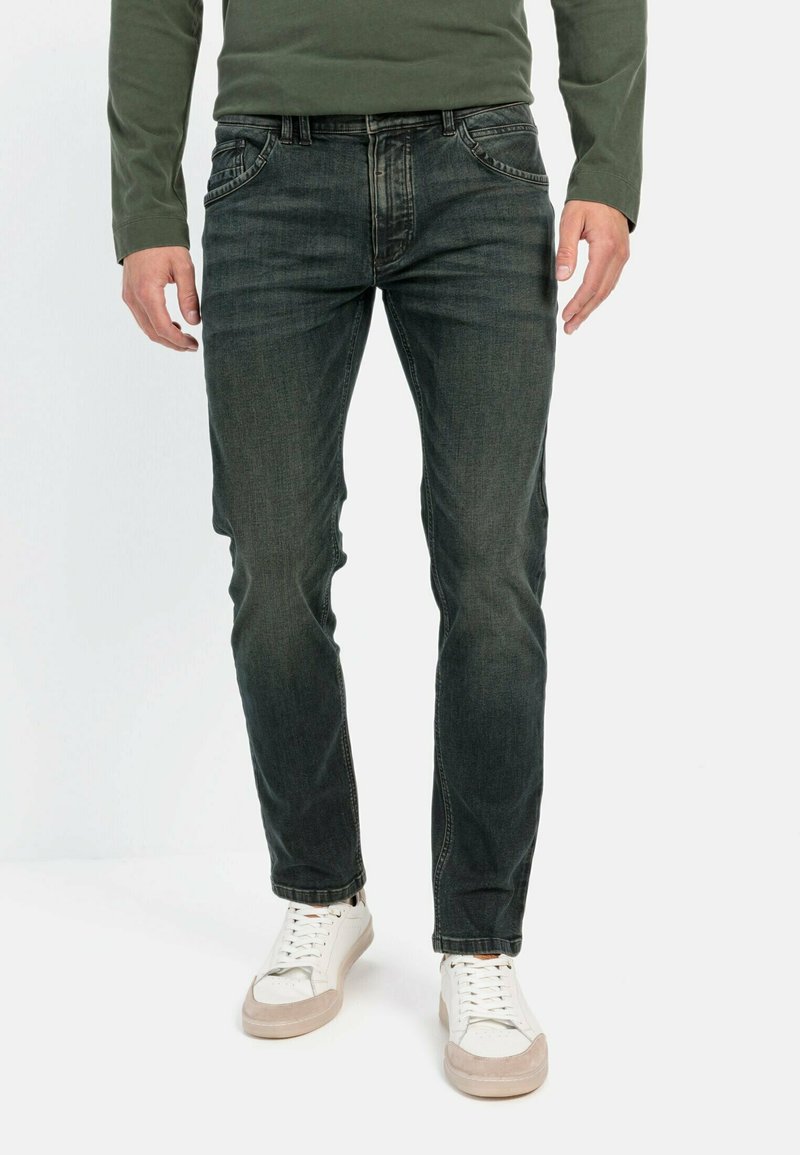 Donkerblauwe denim jeans met een slim fit, vijf pockets ontwerp en subtiele vervaging. Gecombineerd met witte sneakers met beige accenten.