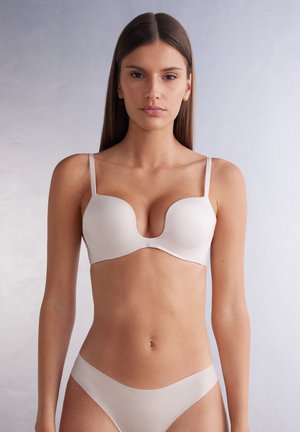 Beige molded underwire bra with thin adjustable straps and smooth texture; paired with matching seamless bikini bottom. Simple design.