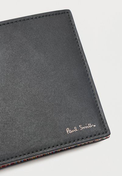 Μαύρο δερμάτινο πορτοφόλι με ραμμένα χείλη και μικρό χρυσό λογότυπο "Paul Smith" στη γωνία, που δείχνει πολύχρωμη ριγωτή εσωτερική άκρη.