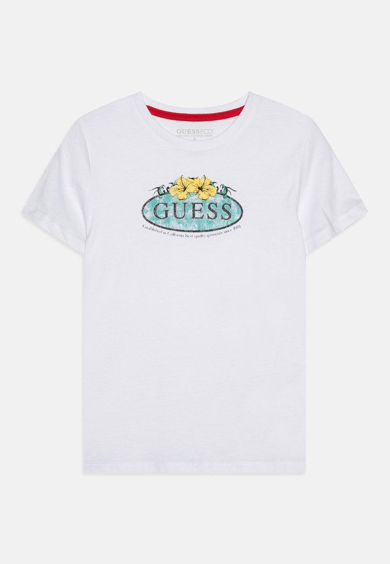 Valkoinen puuvillateepaita, jossa on elävä grafiikka keltaisista kukista ja teal-väreistä, jonka päällä on koristeellinen "GUESS"-teksti.