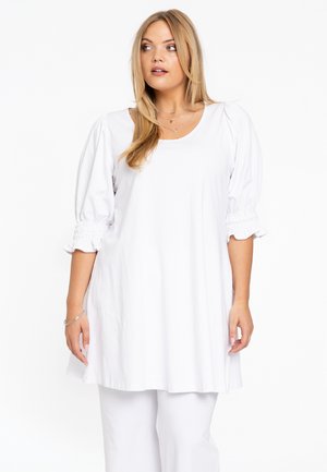 Witte tuniek top met een ronde halslijn en poffende mouwen, voorzien van elastische manchetten. De stof lijkt licht en glad, gecombineerd met witte onderkleding.