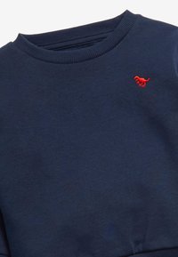 Marineblaues Sweatshirt mit geripptem Kragen und einem kleinen roten Hundelogo auf der Brust. Weicher Stoff mit strukturierter Oberfläche.