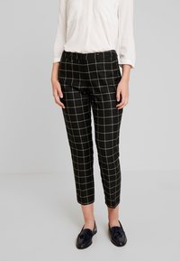 Czarne spodnie w kratę z wzorem siatki, skrócony fason, gładki materiał oraz średni stan, w połączeniu z ciemnymi loafersami i białą koszulą.