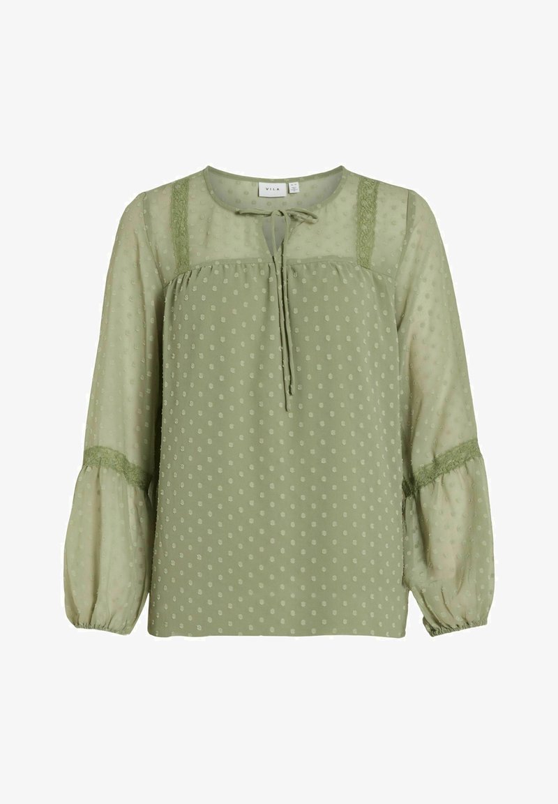 Blouse vert clair à manches longues en tissu transparent à pois, bordure en dentelle aux épaules et aux manches, et nouage devant au niveau de l'encolure.