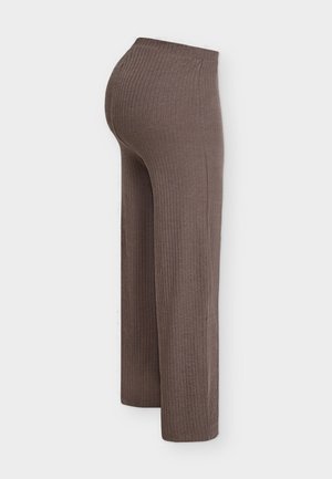 Pantalon large en maille côtelée marron vu de profil, avec une taille haute et une coupe décontractée.