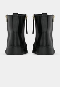 Μαύρα δερμάτινα μποτάκια αστραγάλου με λείο φινίρισμα, διαθέτουν πλευρικό φερμουάρ, θηλιές για να τα τραβάτε και χοντρή σόλα για επιπλέον σταθερότητα.