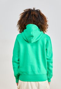 Green hooded sweatshirt with ribbed cuffs and hem. Material appears soft, with a smooth texture. Features a central back seam.