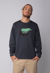 Donker marineblauwe sweatshirt met een groene beer en een bosgrafiek op de voorkant. Heeft een ronde hals en geribde manchetten voor een aansluitende look.