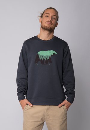 Sweatshirt bleu marine foncé avec un ours vert et un graphique forestier à l'avant. Dispose d'un col rond et de poignets côtelés pour un look ajusté.