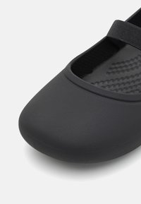 Scarpa piatta nera con punta arrotondata, realizzata in materiale liscio. Presenta una fascia elastica e una soletta testurizzata per il massimo comfort.