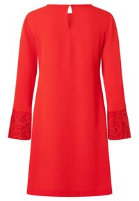 Rode jurk met een keyhole-achterdetail, lange mouwen met bloemenkant accenten op de manchetten, en een gladde, gestructureerde stof.